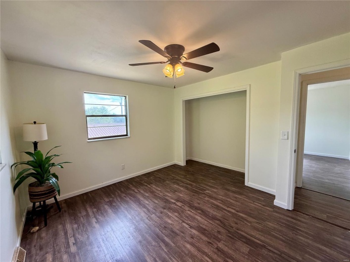 Unfurnished bedroom with a closet, dark wood-type flooring, baseboards, and a ceiling fan