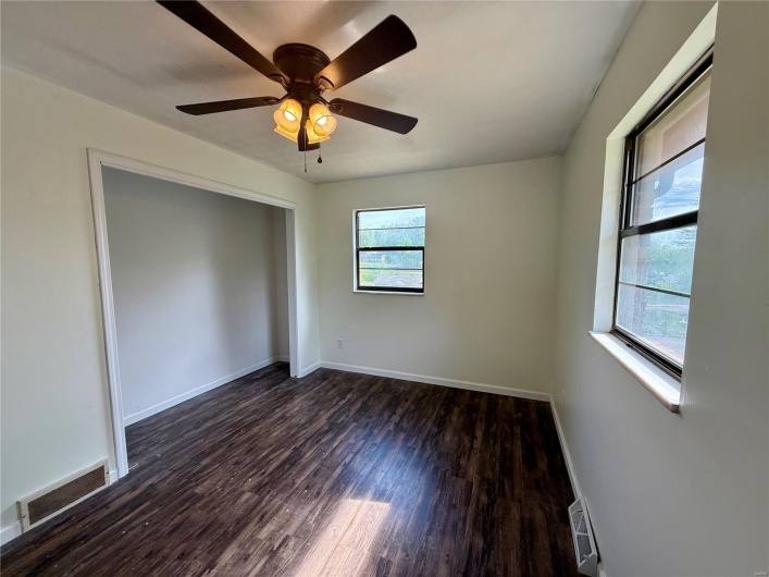 Unfurnished room featuring baseboards, ceiling fan, dark wood finished floors, and visible vents