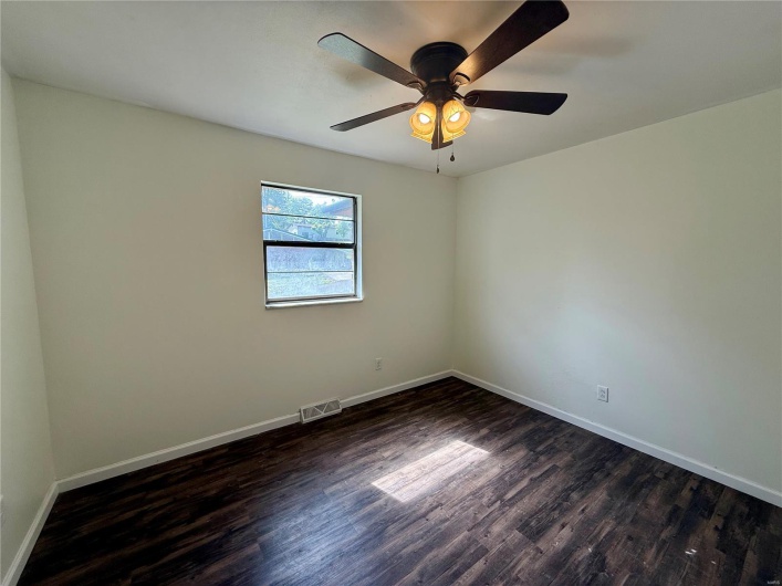 Spare room featuring baseboards, visible vents, and dark wood-type flooring