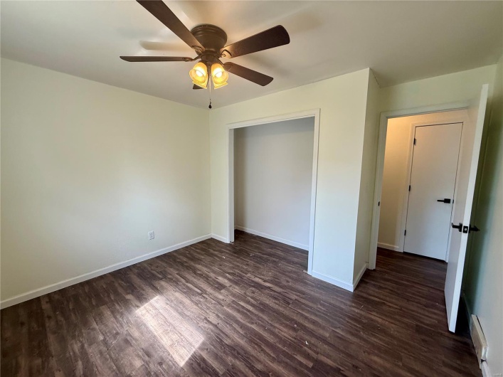 Unfurnished bedroom featuring a ceiling fan, dark wood finished floors, baseboards, and a baseboard radiator