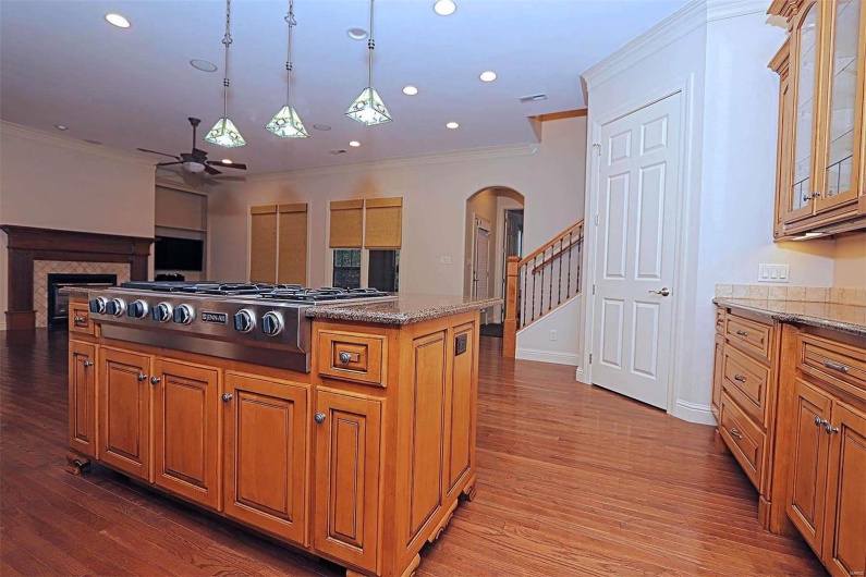 Kitchen with crown molding, hardwood / wood-style flooring, light stone countertops, and ceiling fan