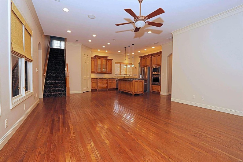 Unfurnished living room featuring sink, crown molding, ceiling fan, and dark hardwood / wood-style flooring