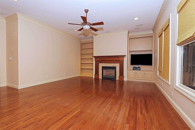 Unfurnished living room with ornamental molding, hardwood / wood-style flooring, a fireplace, and ceiling fan