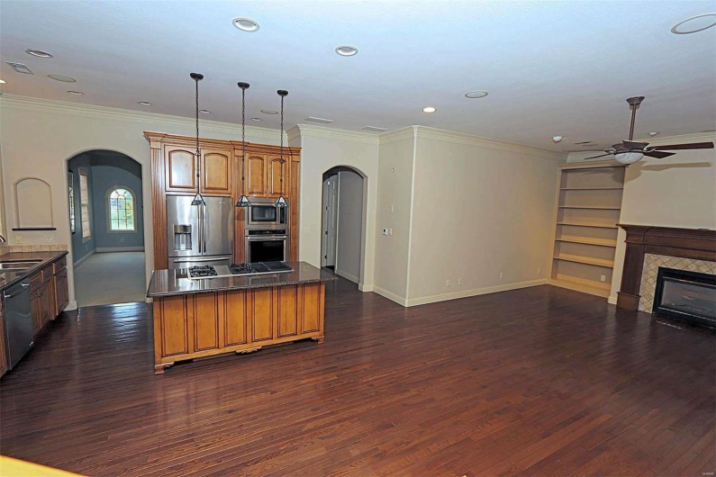 Kitchen featuring ceiling fan, dark wood-type flooring, pendant lighting, crown molding, and stainless steel appliances