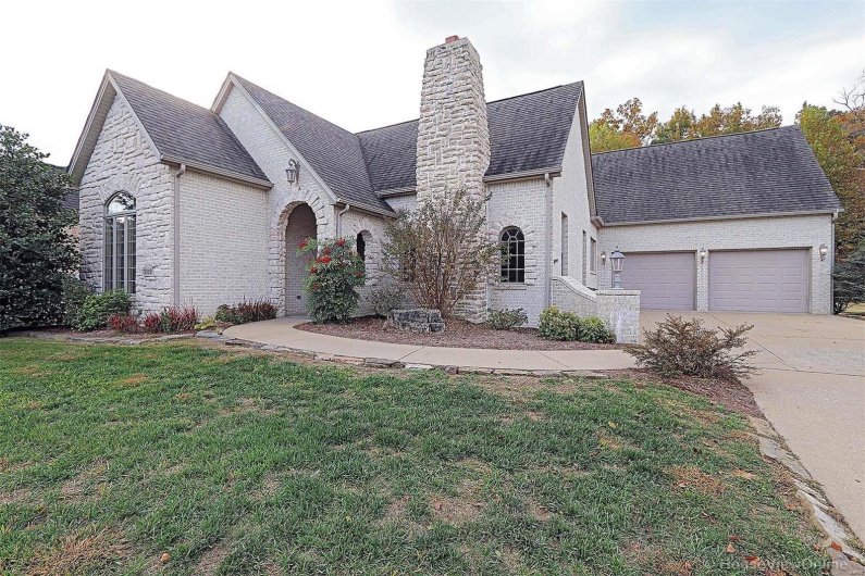 French provincial home featuring a front yard and a garage