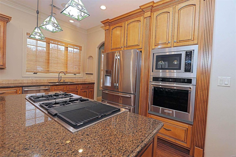 Kitchen featuring appliances with stainless steel finishes, sink, dark stone counters, pendant lighting, and ornamental molding