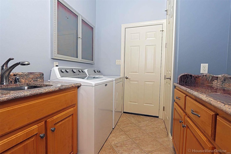 Laundry room featuring light tile patterned floors, cabinets, sink, and washer and clothes dryer