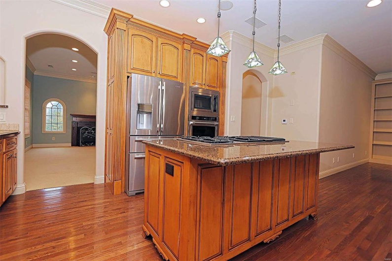 Kitchen featuring a kitchen island, stainless steel appliances, decorative light fixtures, ornamental molding, and dark hardwood / wood-style floors