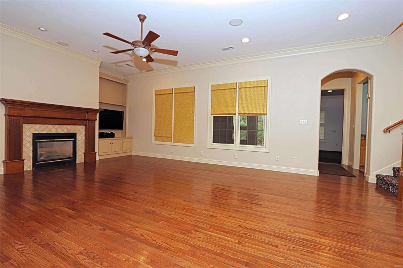 Unfurnished living room featuring crown molding, wood-type flooring, a fireplace, and ceiling fan