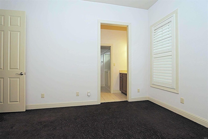 Unfurnished bedroom featuring ensuite bathroom and light colored carpet