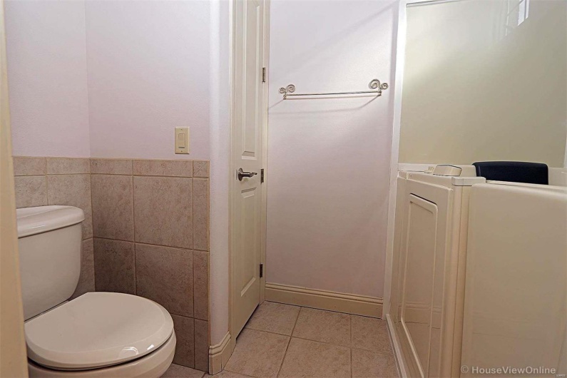 Bathroom with toilet, tile patterned floors, and tile walls