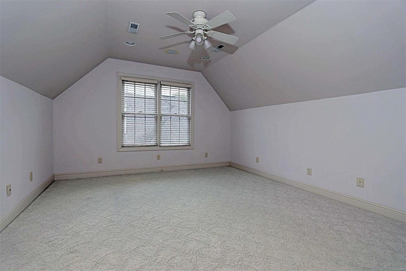 Bonus room with ceiling fan, lofted ceiling, and light colored carpet