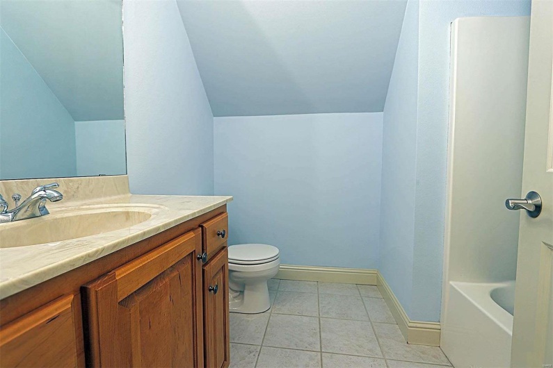 Full bathroom with separate shower and tub, vaulted ceiling, toilet, vanity, and tile patterned flooring