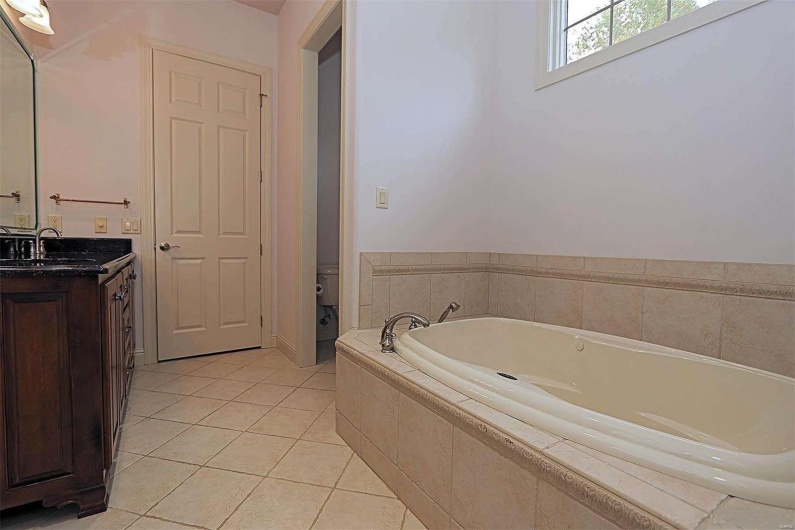 Bathroom featuring vanity, toilet, tile patterned floors, and tiled tub