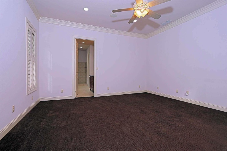 Spare room featuring ceiling fan, ornamental molding, and dark colored carpet