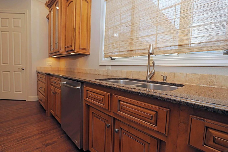 Kitchen with stainless steel dishwasher, sink, and dark wood-type flooring
