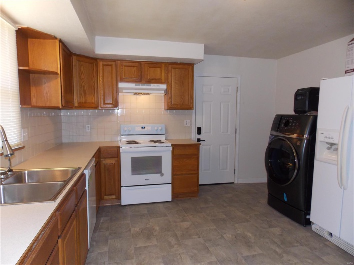 Kitchen featuring white appliances, brown cabinetry, washer / clothes dryer, a sink, and under cabinet range hood