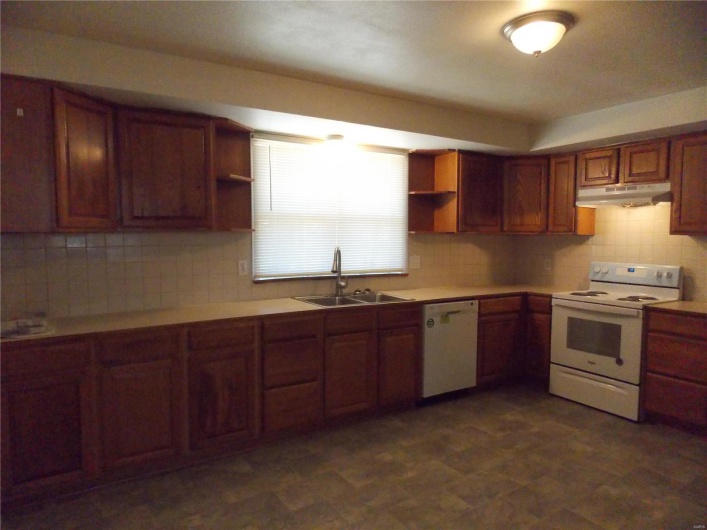 Kitchen with under cabinet range hood, a sink, white appliances, and open shelves