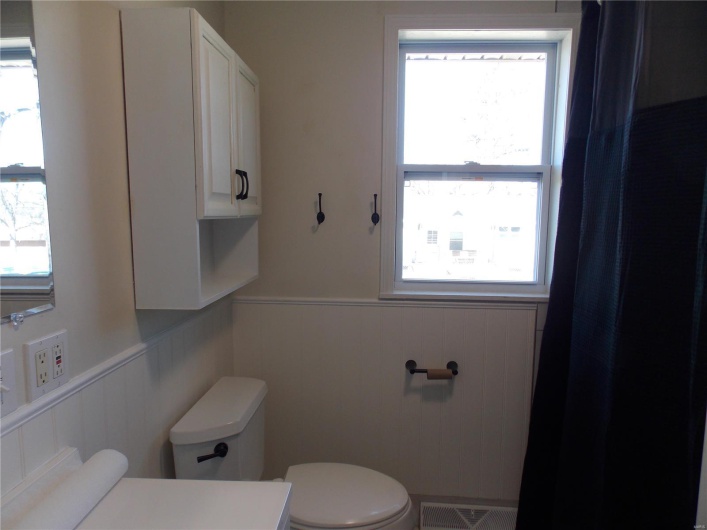 Bathroom featuring visible vents, toilet, a healthy amount of sunlight, and wainscoting