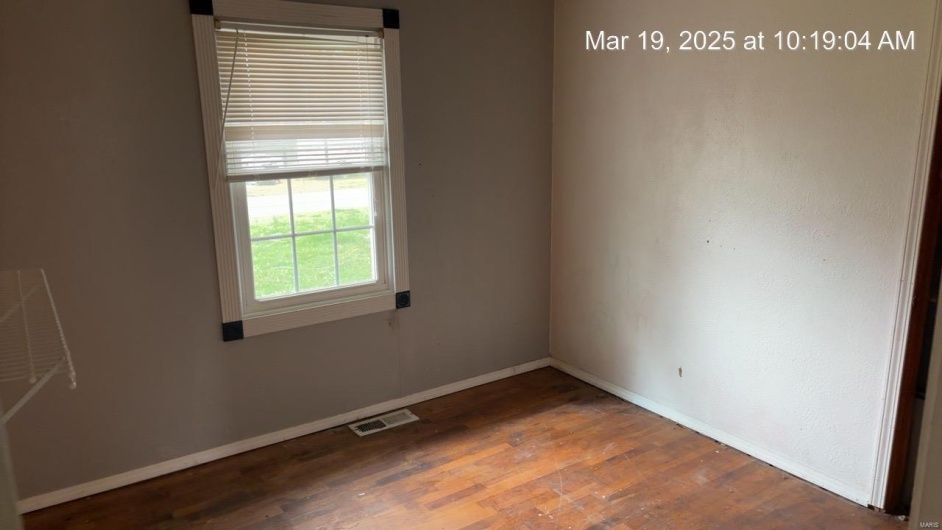 Spare room featuring visible vents, baseboards, and wood finished floors