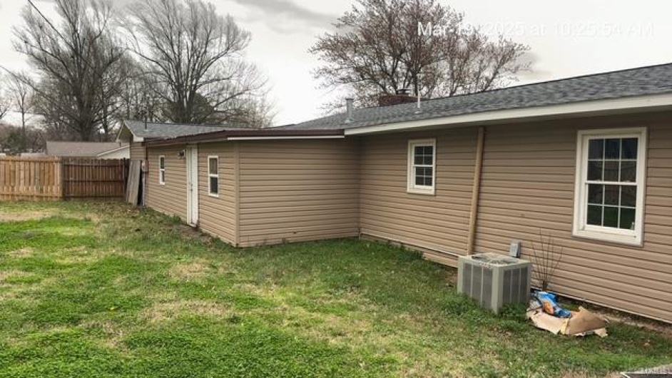 View of side of property with a yard, central air condition unit, and fence