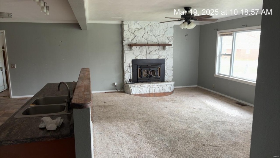 Unfurnished living room with beamed ceiling, baseboards, a ceiling fan, and a sink