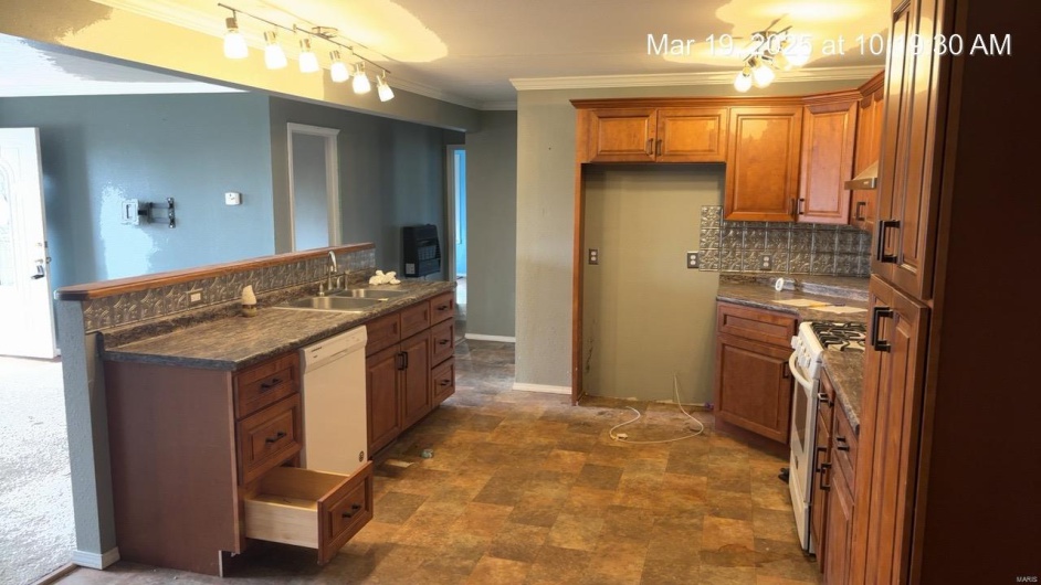 Kitchen featuring dark countertops, brown cabinets, white appliances, and a sink