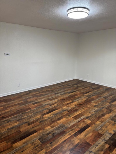 Spare room with dark wood finished floors, baseboards, and a textured ceiling