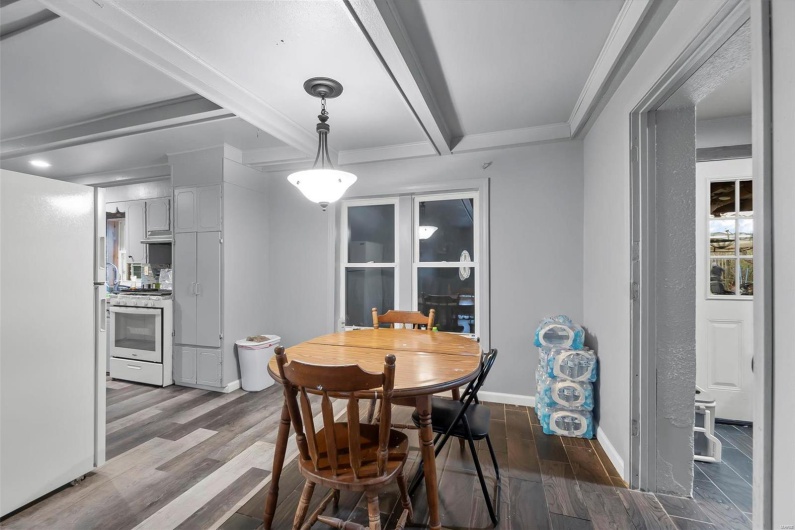 Dining space featuring beam ceiling, crown molding, dark wood-type flooring, and baseboards
