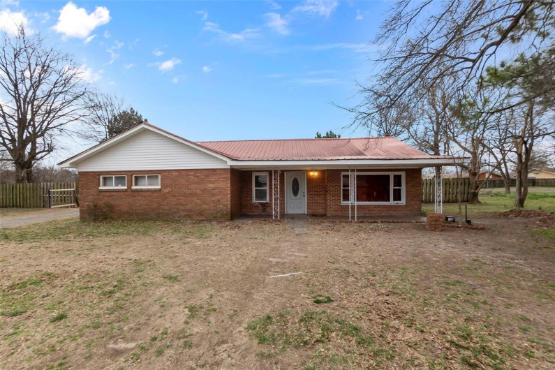 Ranch-style house featuring fence, brick siding, covered porch, and metal roof