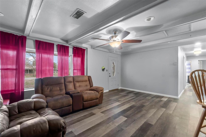 Living room featuring visible vents, baseboards, beamed ceiling, and wood finished floors