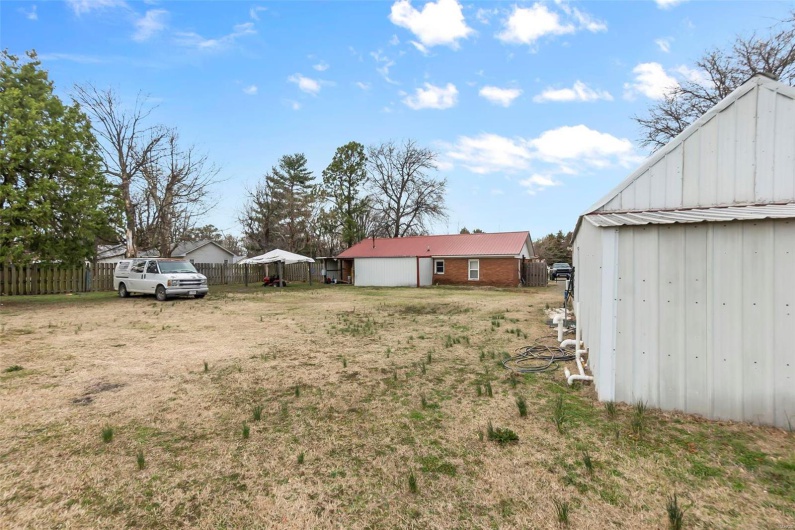 View of yard featuring an outbuilding, driveway, and fence