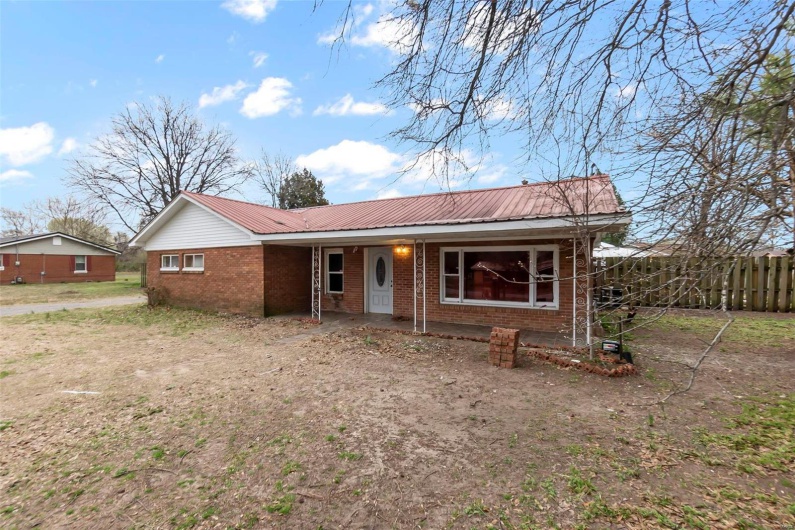 Ranch-style house with brick siding, a porch, metal roof, and fence