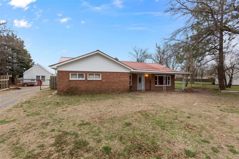 Ranch-style house with brick siding, metal roof, a front yard, and fence