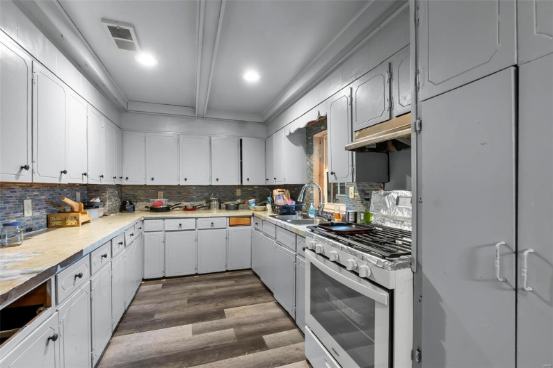 Kitchen featuring visible vents, a sink, decorative backsplash, white gas range oven, and under cabinet range hood