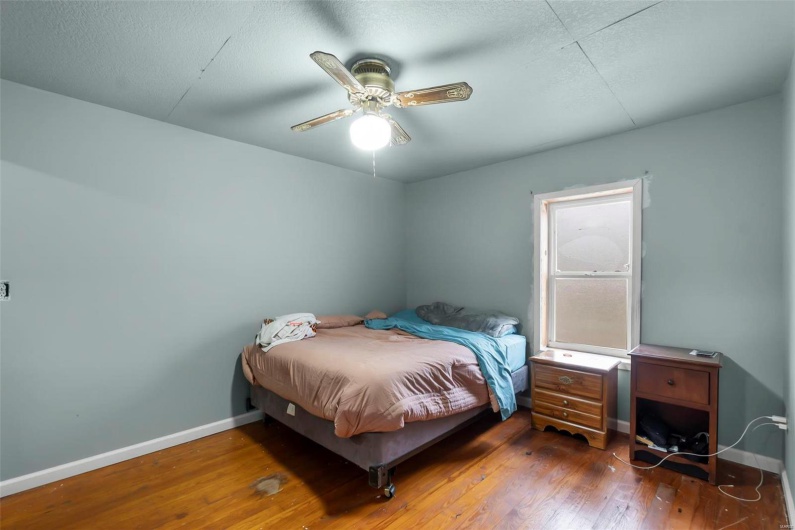 Bedroom with a ceiling fan, baseboards, and wood-type flooring