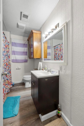 Full bath featuring visible vents, toilet, vanity, wood finished floors, and a textured ceiling