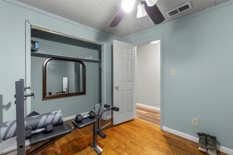Exercise room featuring visible vents, wood finished floors, baseboards, and ceiling fan