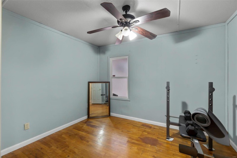 Exercise area featuring baseboards, a ceiling fan, and wood-type flooring