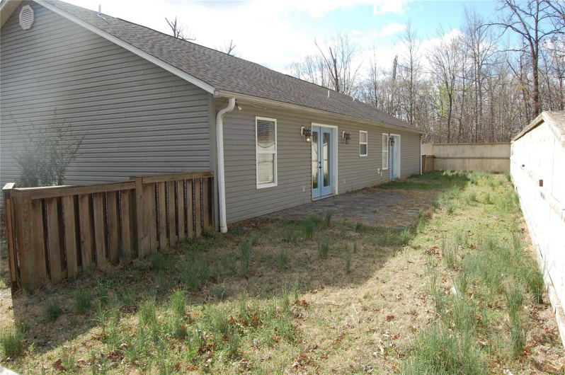 Rear view of house featuring a patio area, french doors, roof with shingles, and fence