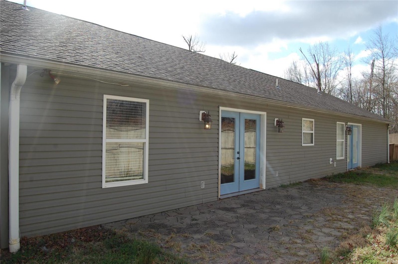 Back of house featuring french doors, roof with shingles, and a patio area
