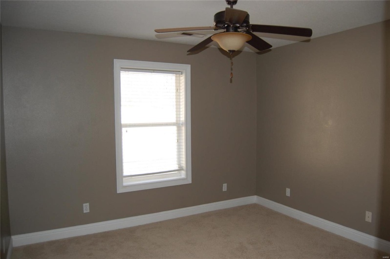 Spare room featuring light colored carpet, baseboards, and ceiling fan