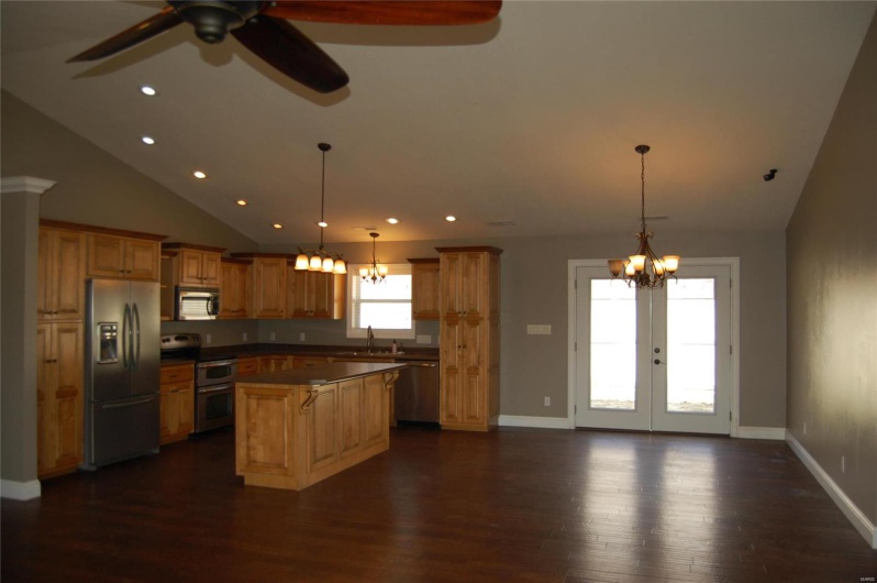 Kitchen with a kitchen island, dark wood-style flooring, french doors, appliances with stainless steel finishes, and ceiling fan with notable chandelier