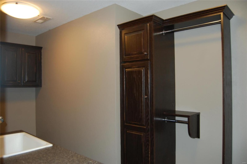 Kitchen with dark brown cabinetry, dark countertops, visible vents, and a sink