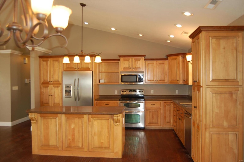 Kitchen featuring dark wood-type flooring, dark countertops, recessed lighting, appliances with stainless steel finishes, and vaulted ceiling