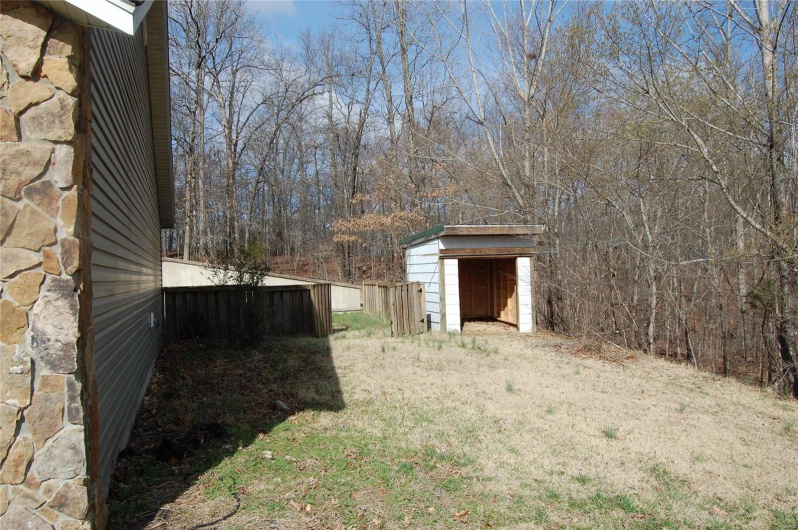 View of yard featuring an outbuilding, a storage shed, and fence