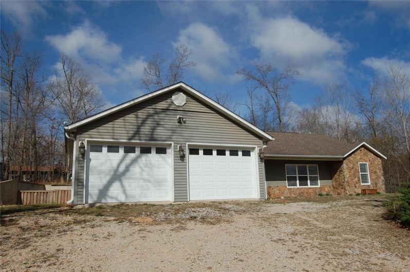 Ranch-style house featuring stone siding and dirt driveway