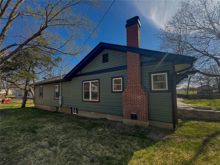 View of property exterior featuring a lawn and a chimney
