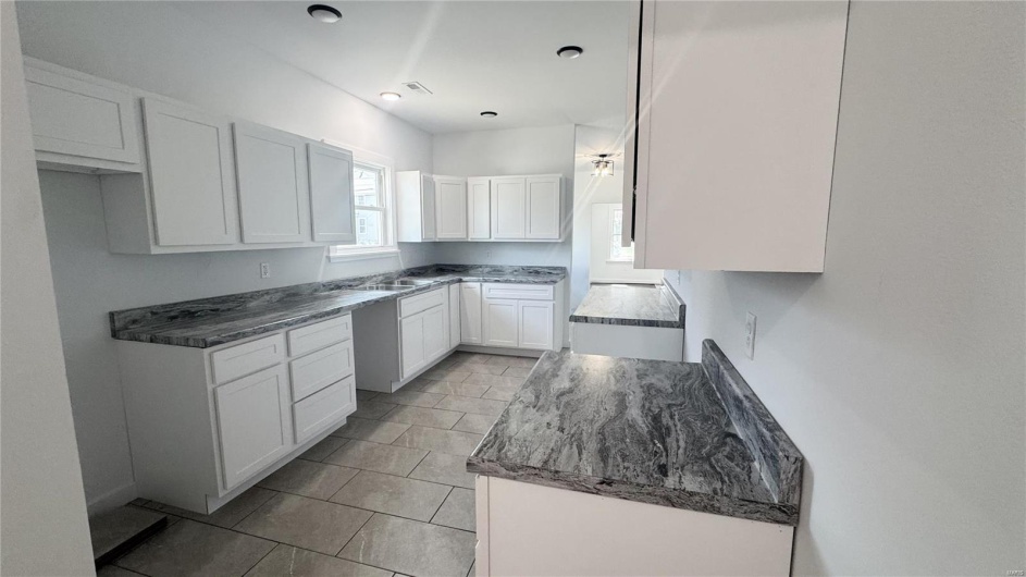 Kitchen featuring white cabinets, a sink, and light tile patterned floors