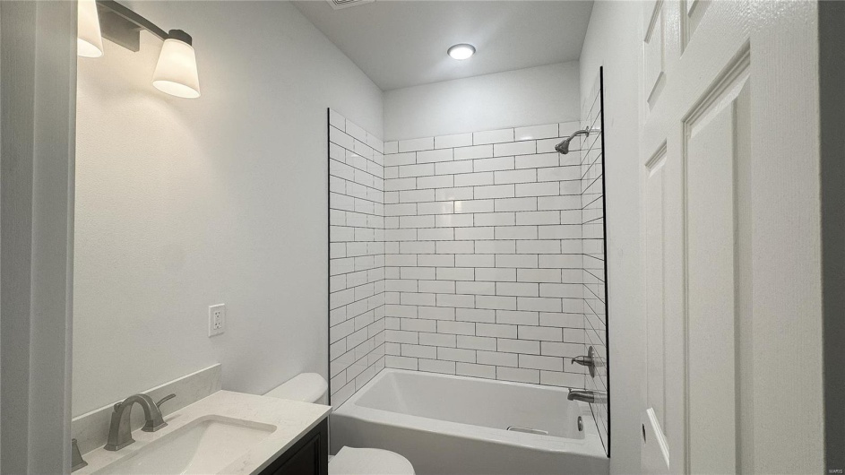 Bathroom featuring toilet, vanity, and bathing tub / shower combination